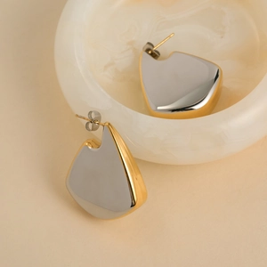 Macro detail of high-polish two-tone fan-shaped 18K gold plated titanium steel earrings