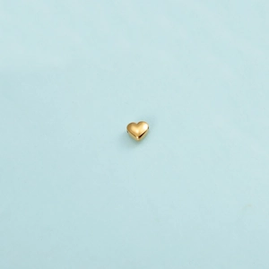 Macro shot of a polished gold heart-shaped bead with small aperture for jewelry making