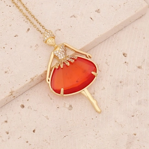 Elegant gold ballerina dancer pendant necklace with orange gemstone on stone background