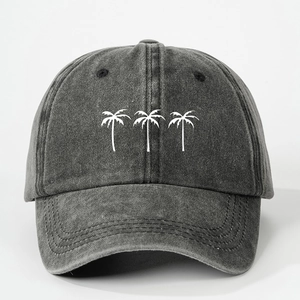 Close-up of three white coconut trees embroidery on a dark grey washed denim baseball cap