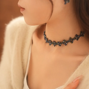Close-up of iridescent beaded choker necklace and floral diamond stud earrings on a model
