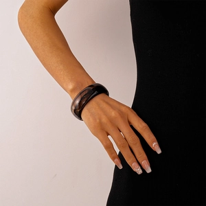 Detail eines braunen, lichtdurchlässigen Acryl-Armbands an einem Handgelenk