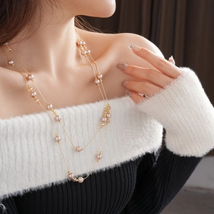 Close-up of double-layer gold chain necklace with pink pearls worn by a model
