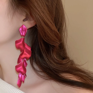Macro detail of long matte red petal tassel earrings worn by a model in close-up view