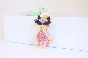 Close-up of cute cat keychain with pink and black rhinestones on a gold metal base