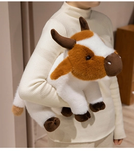 Detailed view of a soft plush brown and white stuffed cow doll held in hand