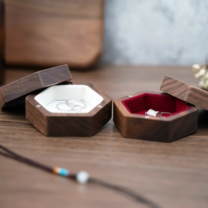Close-up of hexagonal walnut wood jewelry boxes with white and red velvet linings