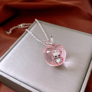 Detail of pink resin apple pendant with shimmering pavé bear inside on silver chain
