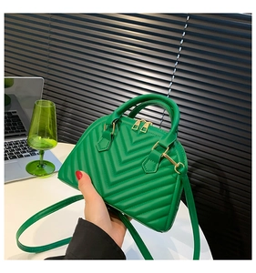 Detail of green shell bag featuring quilted V-pattern leather and dual handles
