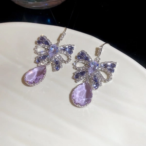 Detail of butterfly bow earrings with purple teardrop gemstone and sparkling zircon stones