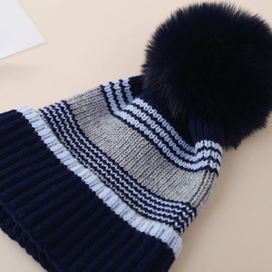 Détail d'un bonnet rayé avec pompon montrant la texture côtelée et la qualité du fil