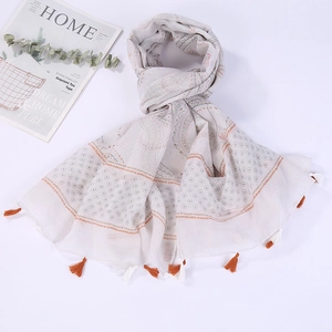 Detail of beige beach scarf with geometric patterns and tassels on white background