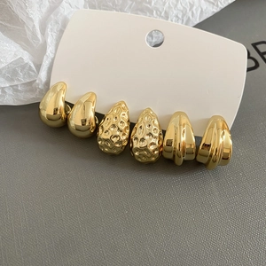 Detailed view of three pairs of gold-plated stud earrings in smooth, hammered, and striped textures
