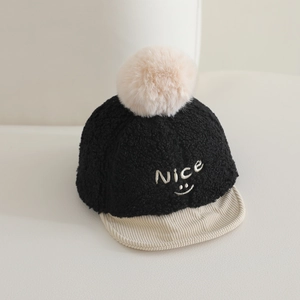 Détail de casquette bébé avec broderie sourire et grand pompon en peluche doux