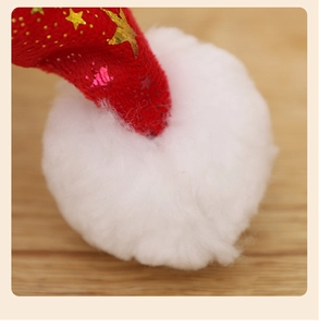 Close-up of a red plush Christmas hat with gold stars and a fluffy white pom-pom tip