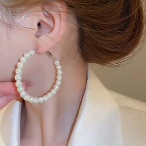 Close-up of elegant white pearl hoop earrings worn by a model in soft lighting