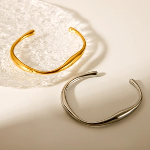 Detail view of irregular liquid metal bangles in gold and silver on glass plate