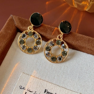 Détail de boucles d'oreilles étoile et cœur en or avec cristaux noirs sur velours brun