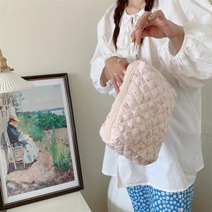 Mannequin tenant une trousse à cosmétiques rose matelassée avec motifs dans un salon doux