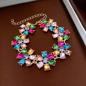 Detailed shot of a gold floral link bracelet featuring colorful oval gemstones on a dark base