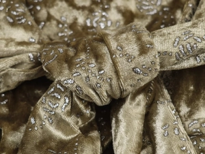 Macro shot of gold velvet fabric with silver metallic details and elegant draping
