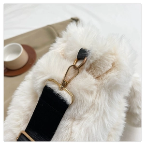 Close-up of golden metal buckle and black strap on plush white faux fur tote bag