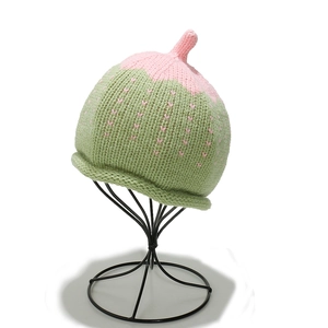 Détail du bonnet en tricot vert pour bébé avec motifs fraises et pointe décorative