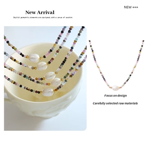 Detail of colorful tourmaline beaded necklace with white pearl pendant on ceramic cup