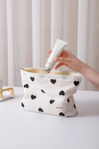 Close-up of heart pattern makeup bag showing interior space and branded woven label