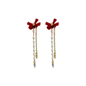 Detail of red velvet bow earrings with gold tassels, white pearls and crystal drops
