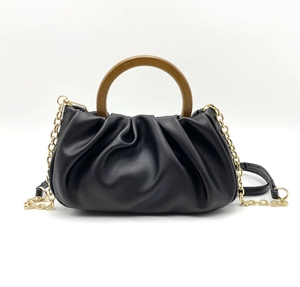 Detail of black pleated cloud bag featuring a vintage semicircular wooden handle and gold chain