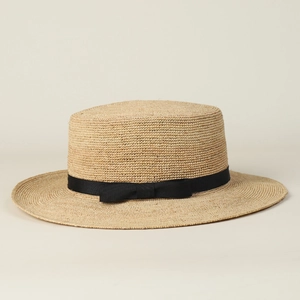Detailansicht der handgeflochtenen Raffia-Strohstruktur und schwarzen Bandschleife am Sonnenhut