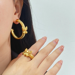 Détail de boucles d'oreilles spirales dorées et bague avec design nœud en acier 316