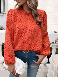 Detail of orange hollow embroidery shirt showing stand collar and puff sleeve texture