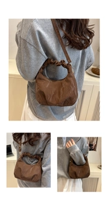 Detail of a brown pleated crescent bag with ruched handle and adjustable strap