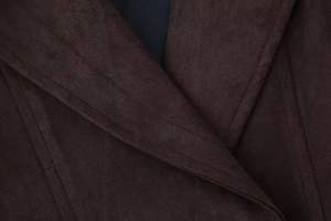 Vue macro de la texture en daim marron foncé et de la double couture sur la veste à revers