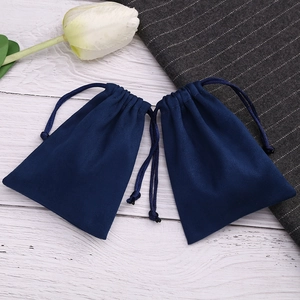Detailed view of dark blue velvet drawstring pouches on a white wooden tabletop decor