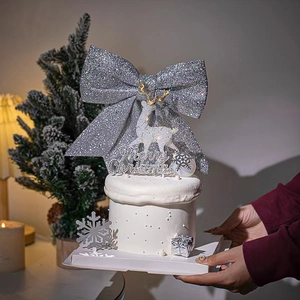 Macro detail of silver glitter bow with white reindeer and Merry Christmas cake topper