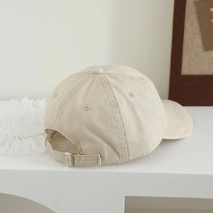 Détail de la casquette beige en coton avec coutures de qualité et boucle de réglage en métal
