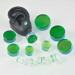 Élargisseurs d'oreilles en verre dégradé vert et bleu sur un modèle d'oreille noir