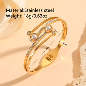 Bracelet jonc doré en acier inoxydable avec perles et strass sur fond beige chaud