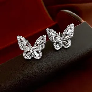 Boucles d'oreilles papillon en argent avec zircons sur présentoir en cuir marron