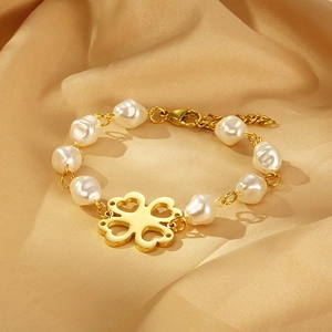 Detail of clover pearl bracelet with hollow heart charms on golden lobster clasp