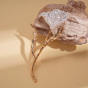 Macro detail of metallic flower brooch with silver petals and golden textured stem