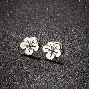 Macro shot of silver cutout flower earrings with intricate petal texture and butterfly backs