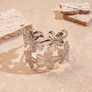 Detail of silver metallic double-layer flower open bangle on textured stone background