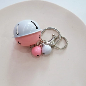 Detailed macro of pink and white lacquered metal bells with braided cord keychain