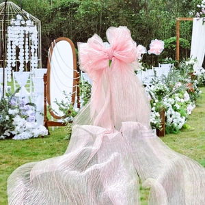 Detailed view of pink pleated tulle oversized bow decor for outdoor wedding ceremony