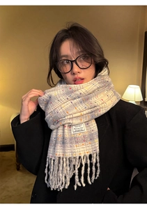 Detail of grey plaid scarf with colorful dots, fringe hem and woven text label on model