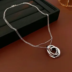 Elegant silver interlocking triple ring necklace with zircon on brown leather background